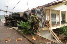 Caminhão perde controle e tomba sobre residência