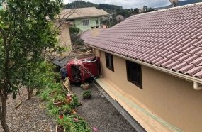 Veículo capota em pátio de residência após colisão 