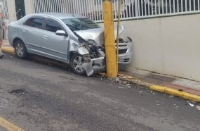Carro colide contra poste após atingir veículos estacionados 