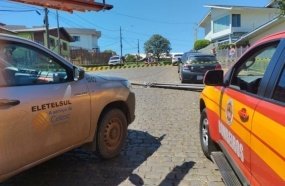 Caminhão enrosca em fios da rede elétrica e derruba poste sobre veículo 