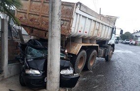 Carro fica destruído após ser prensado por caminhão caçamba